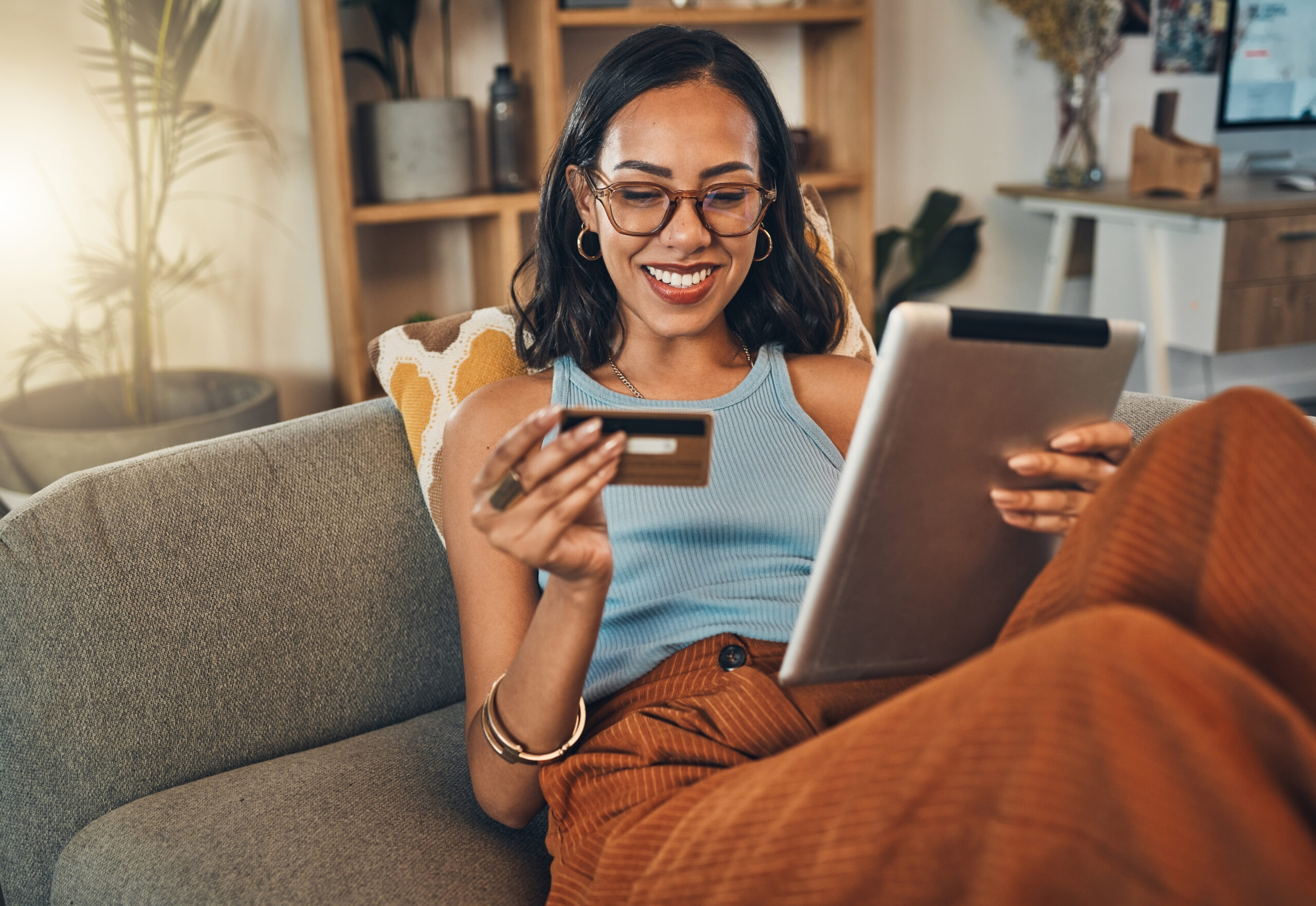 Smiling mixed race woman using credit card for ecommerce on digital tablet at home