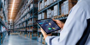 A warehouse worker checks his inventory management app to see insights about product demand.