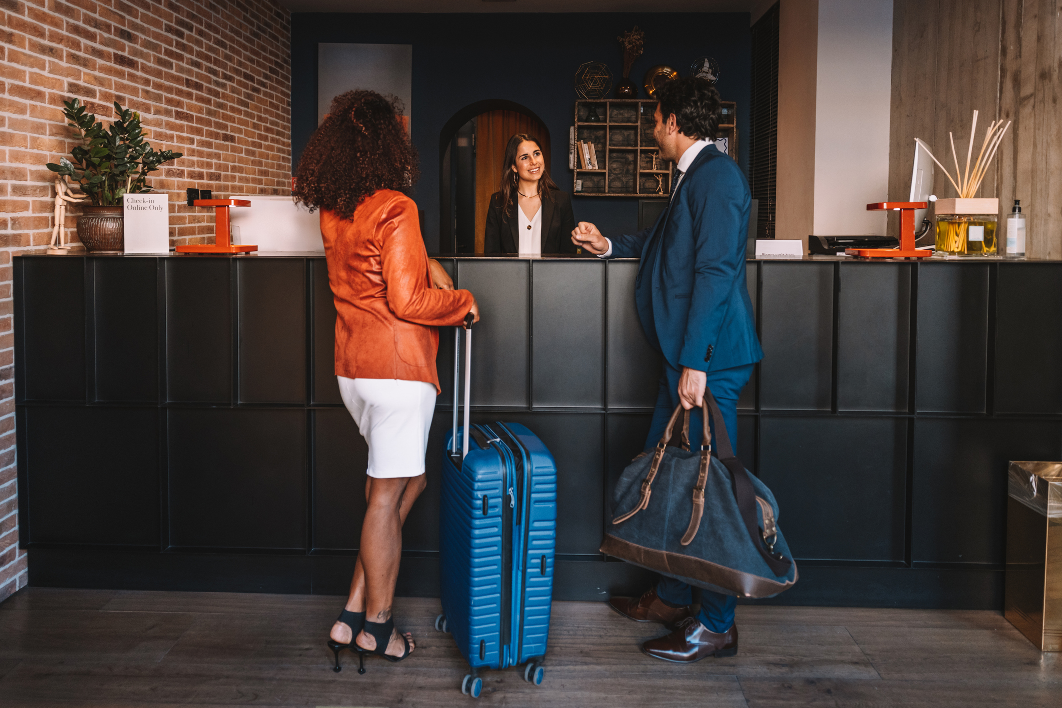 Receptionist in a luxury hotel welcoming two business guests at the hotel lobby.